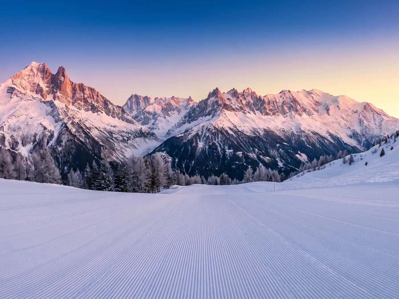 Freshly groomed piste at first light with the Aiguilles de Chamonix and Mont Blanc behind