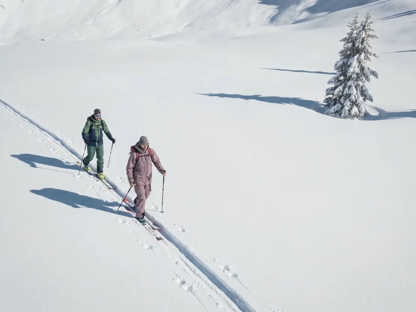 Deux randonneurs à skis montent sur une trace dans la neige fraîche